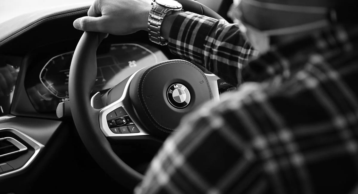 Chauffeur VTC devant sa berline noire dans une rue urbaine parisienne