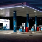 Main posant un pistolet à essence sur une voiture, station-service en arrière-plan