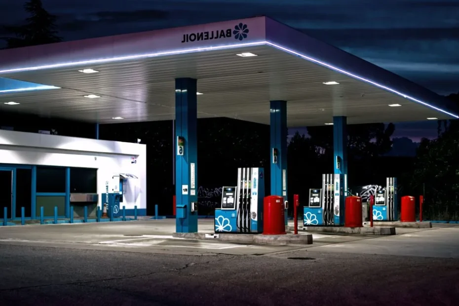 Main posant un pistolet à essence sur une voiture, station-service en arrière-plan
