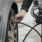 Recharger sa clim de voiture soi-même vaut-il vraiment le coup ? Mécanicien connectant un manomètre au port basse pression d'un circuit de climatisation automobile
