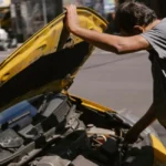 Mécanicien installant une batterie 70Ah dans un compartiment moteur de voiture