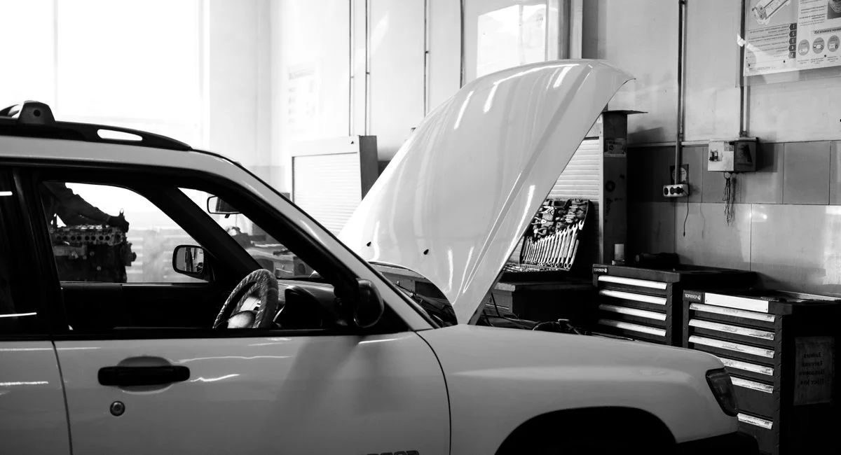 Mécanicien testant la batterie d'une voiture avec un multimètre sous le capot