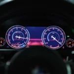 Tableau de bord allumé avec voyant moteur orange sur une voiture en circulation