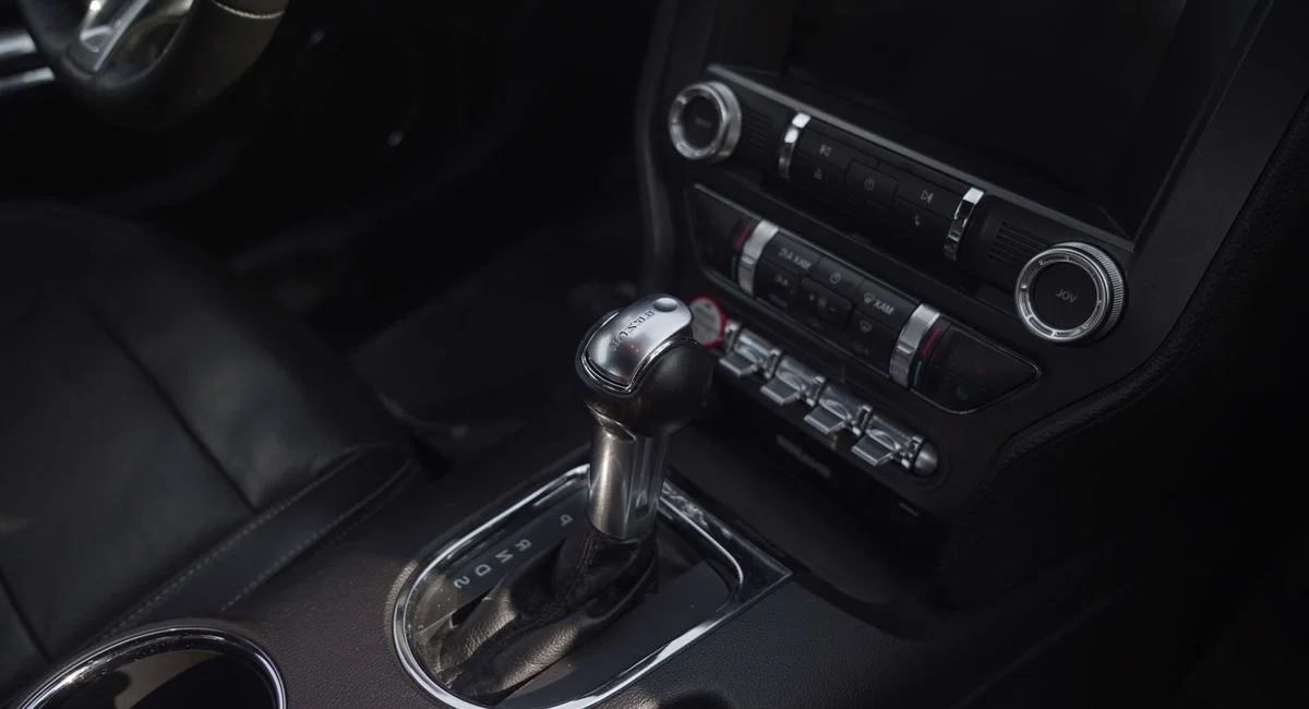 Technicien Norauto effectuant une vidange de boîte automatique sur une voiture surélevée