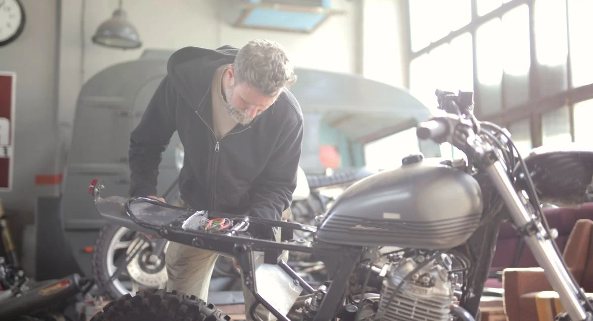 Technicien versant huile de fourche dans suspension moto Ohlins atelier