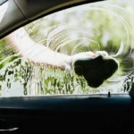Gros plan sur une main tenant des jetons lavage devant une station auto