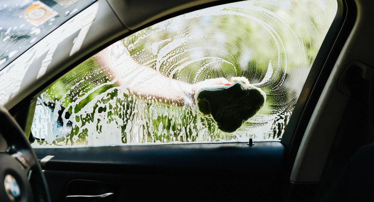 Gros plan sur une main tenant des jetons lavage devant une station auto