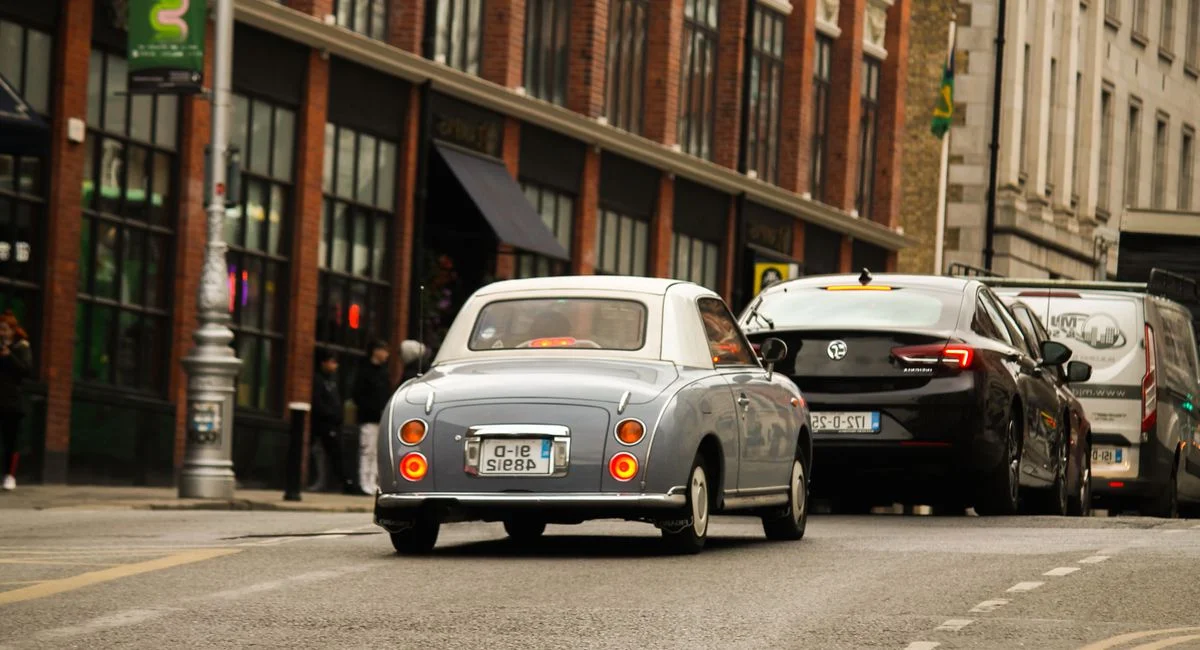 Véhicules de collection et électriques garés sur une avenue urbaine