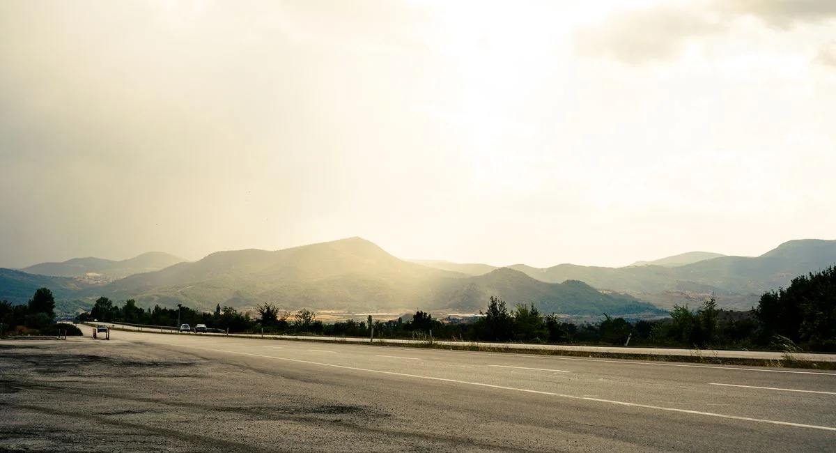 A serene highway view with distant mountains under a bright sky, capturing tranquility and natural beauty.