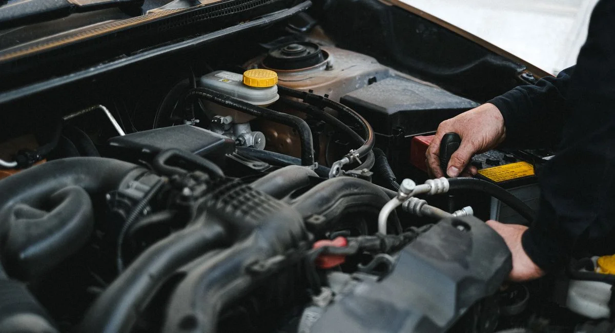 Close-up of a mechanic's hands working on a car engine, showcasing repair work.