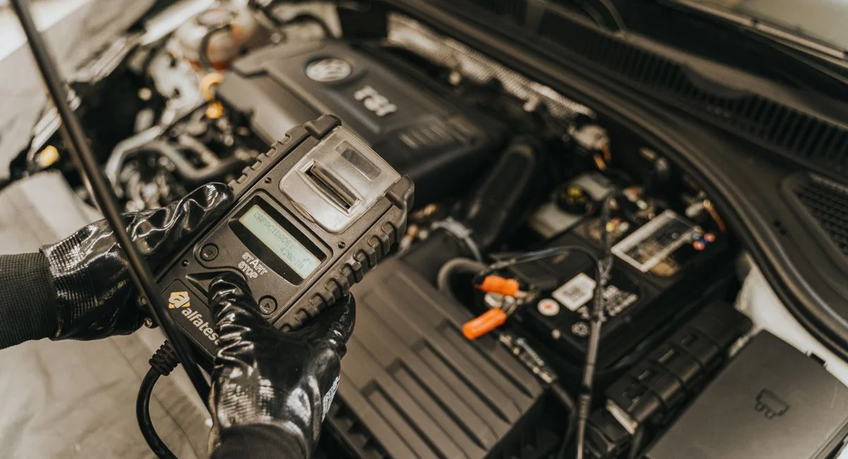Mechanic diagnosing a car engine with a diagnostic tool, showcasing technical expertise and automotive care.